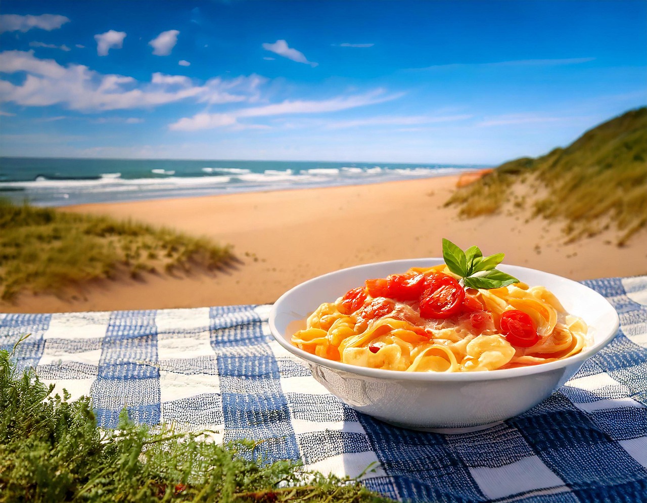 Pasta fredda estiva con pomodorini, basilico e mozzarella, pronta per essere gustata in spiaggia.
