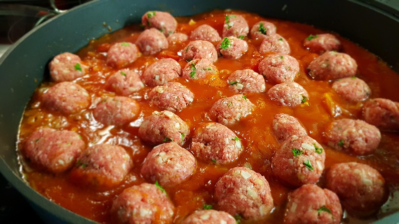 Polpette alla pizzaiola servite su un piatto, accompagnate da salsa di pomodoro e basilico fresco.