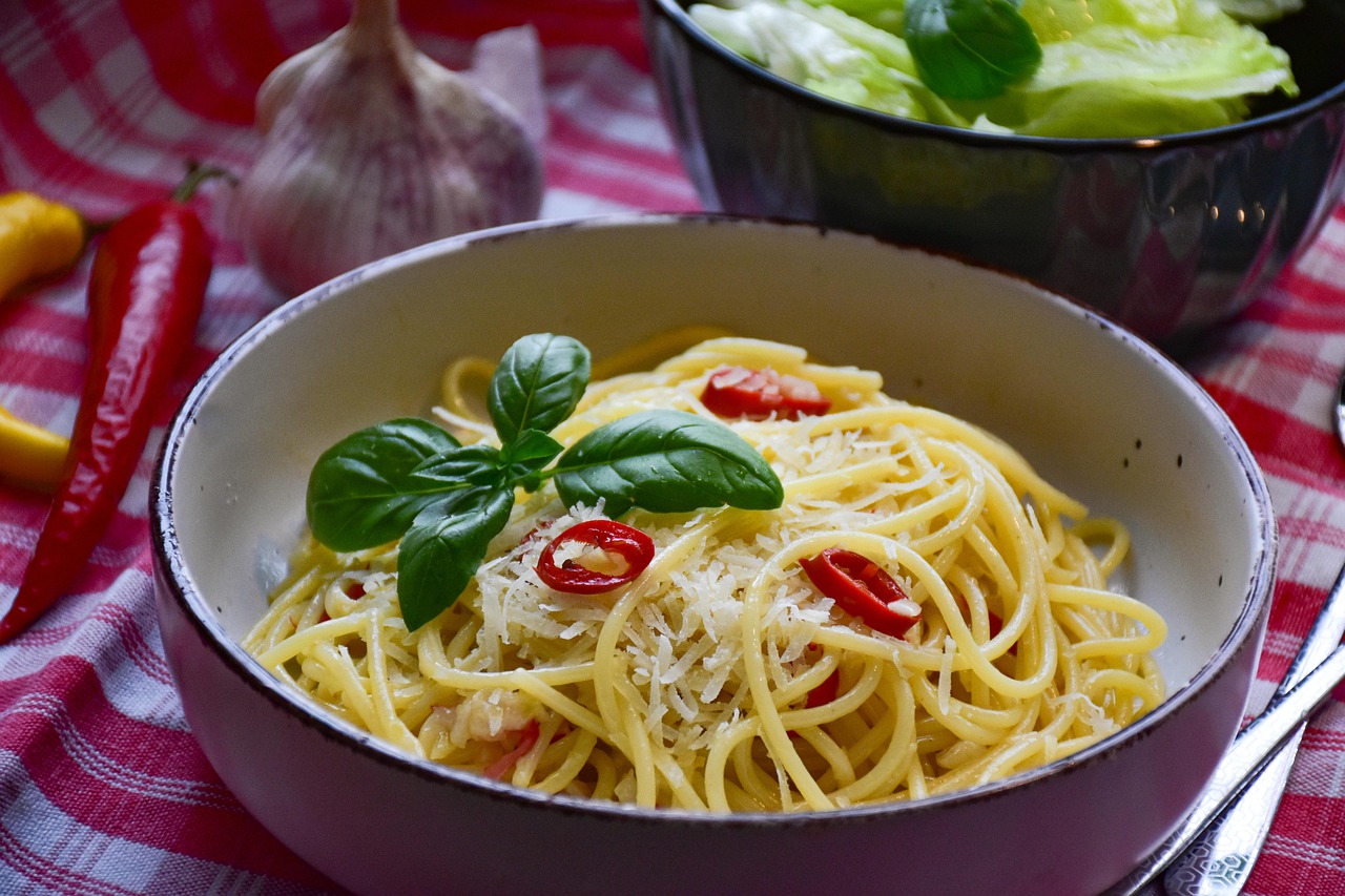 Pasta aglio olio e peperoncino gourmet servita su piatto elegante con decorazioni di erbe fresche.