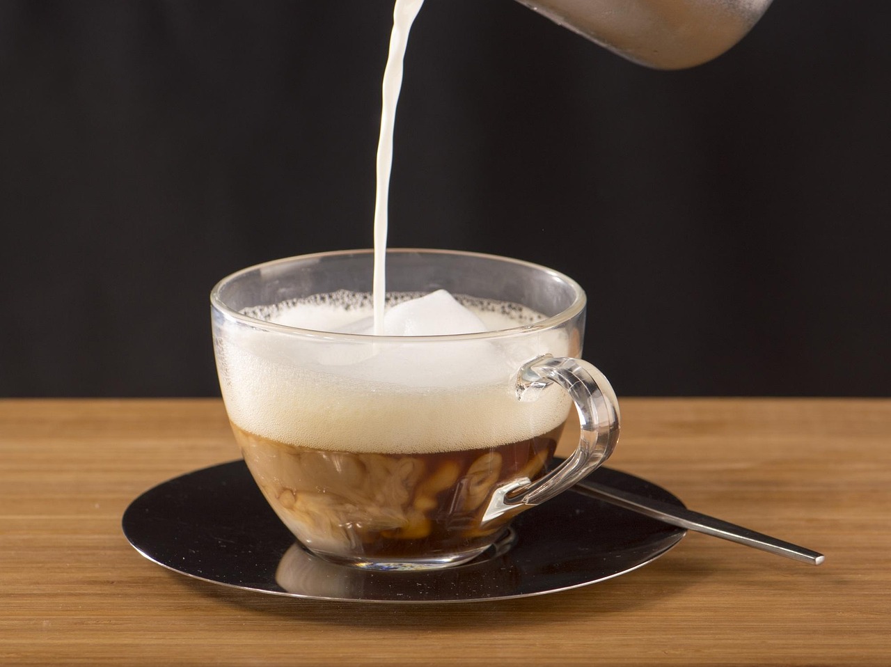 Tazza di caffè con latte freddo, decorata con schiuma, su un tavolo di legno.