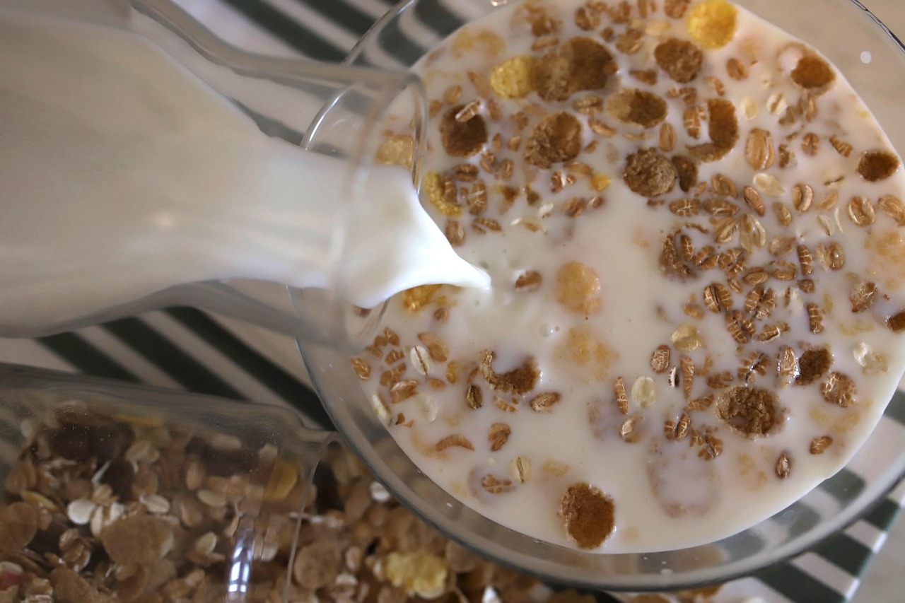 Tazza di latte d'avena con cereali e frutta fresca su un tavolo da colazione.